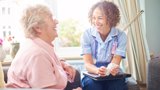 A nurse engages in conversation with an elderly woman, providing care and support in a warm, compassionate setting.